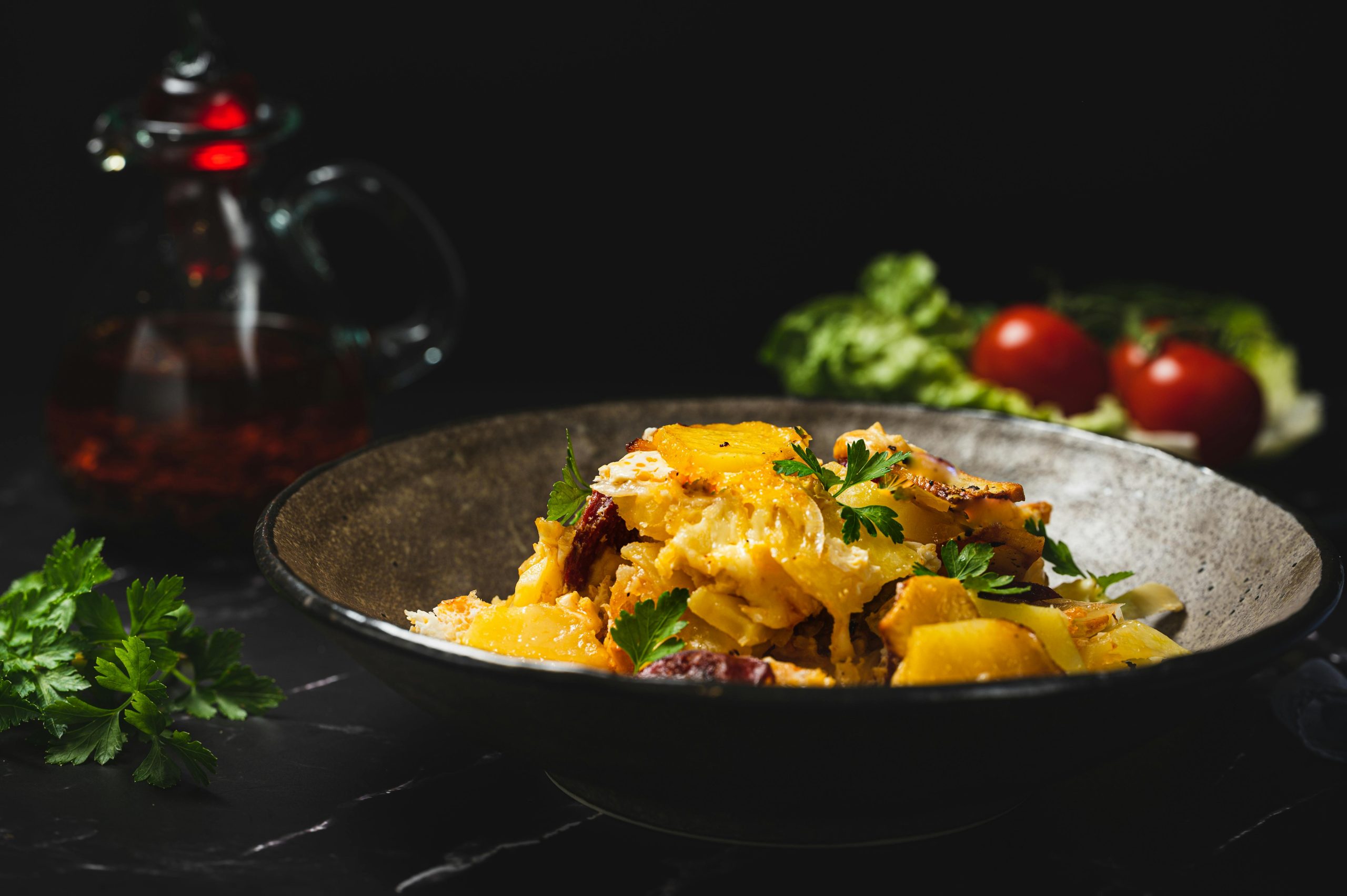 Close-up of a delicious pasta dish garnished with parsley and vegetables on a dark background.